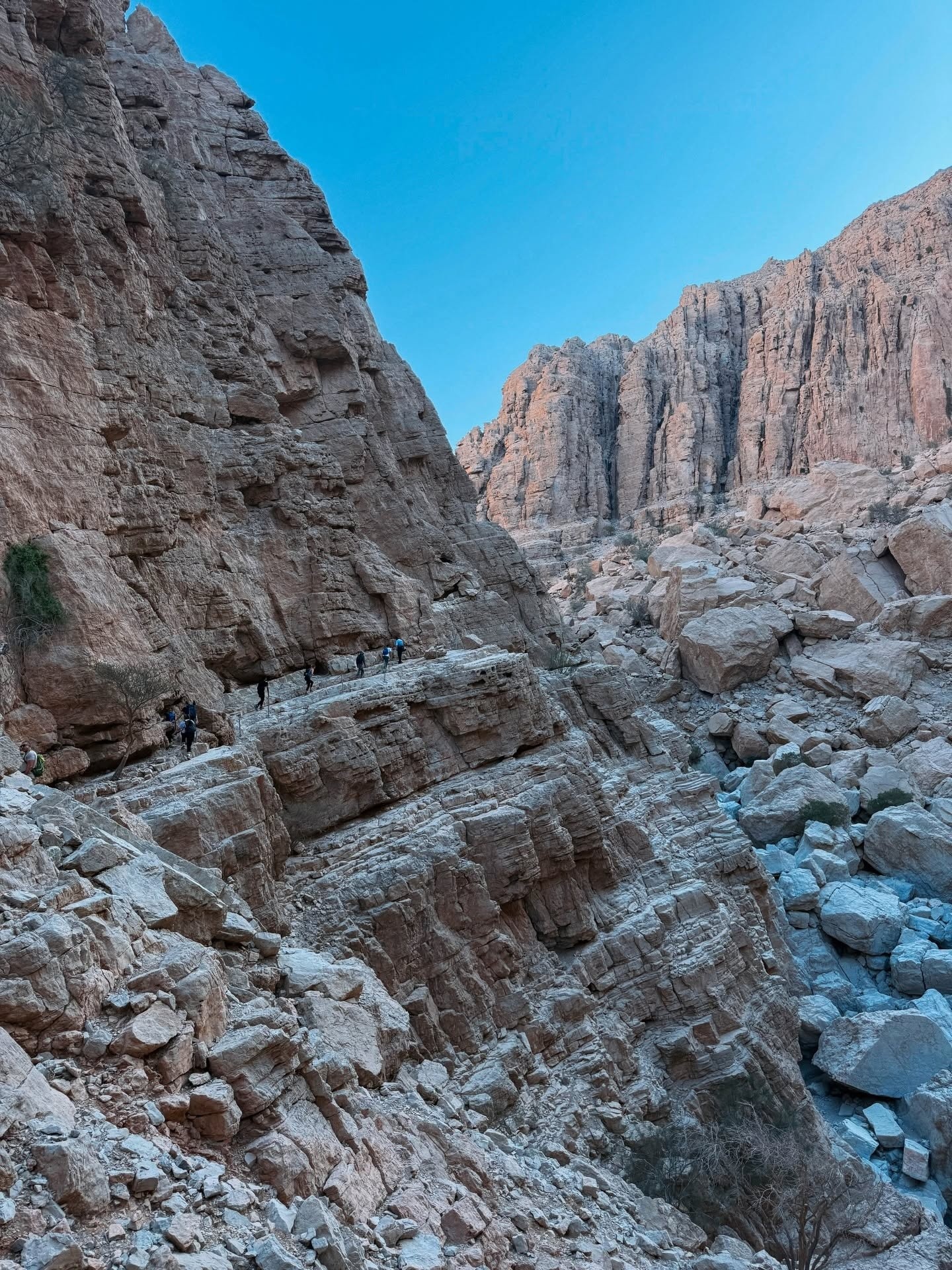 Rocky canyon with boulders and clear blue sky above.