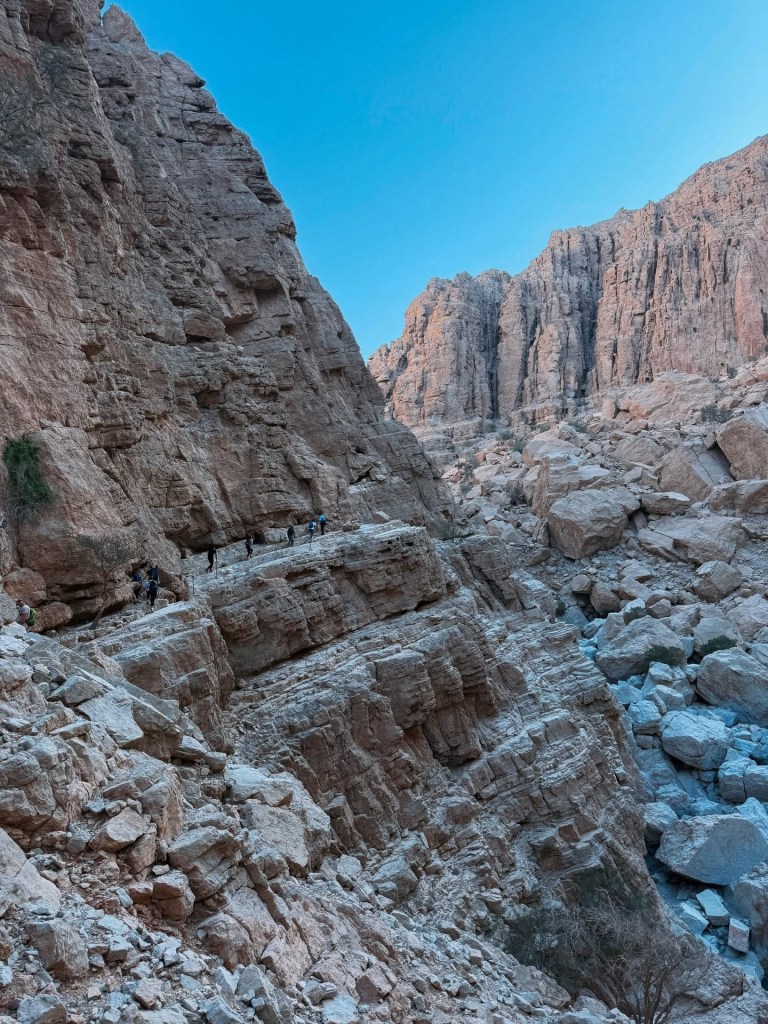 Rocky canyon with boulders and clear blue sky above.