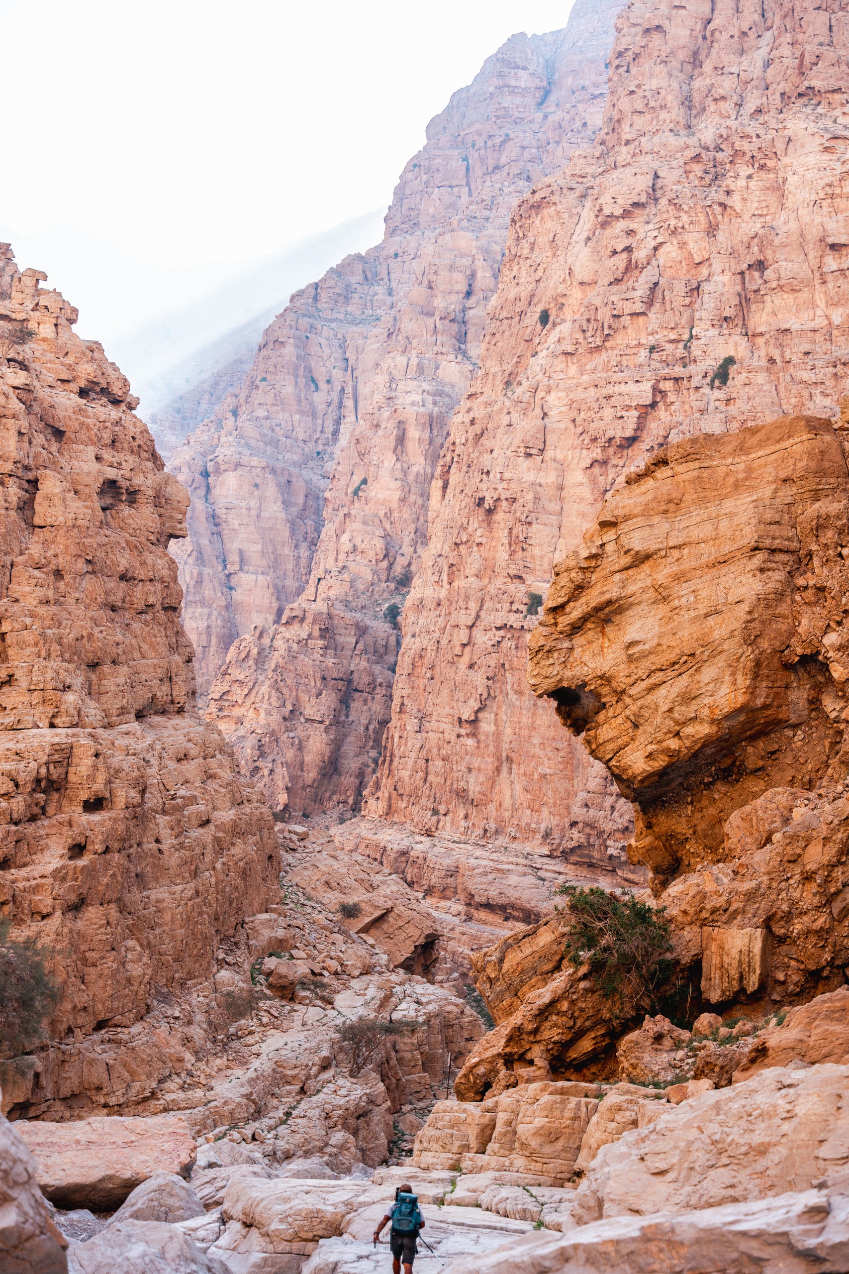 Hiker walking through a narrow canyon with steep rocky walls.